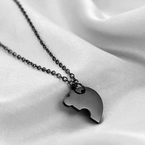 Fashionable black heart puzzle pendant necklace in polished stainless steel on white silk