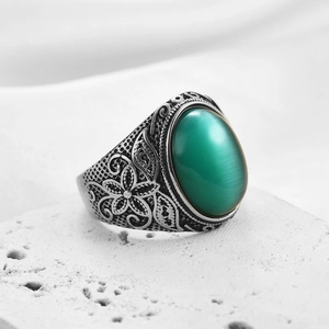 Dettaglio della pietra occhio di gatto verde e incisioni floreali su anello vintage