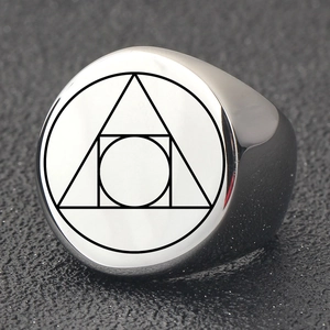 Macro shot of polished stainless steel ring with nested geometric symbols on a flat surface