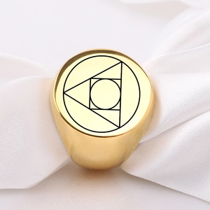 Macro detail of gold stainless steel signet ring with engraved geometric alchemy symbol