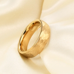 Macro shot of 6mm gold hammer textured stainless steel ring on soft cream satin fabric