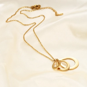 Polished gold teardrop pendant necklace with three nested loops on silk background