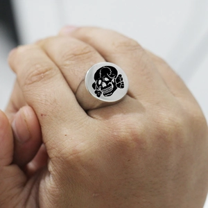 Detailed close-up of a silver titanium steel signet ring featuring a black skull design