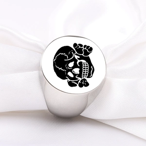 Detailed macro view of silver titanium steel signet ring with black skull design on white silk