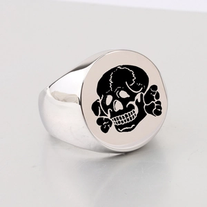 Detailed close-up of a silver stainless steel signet ring with a laser-etched skull design