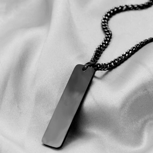Macro shot of minimalist black stainless steel bar pendant with matching Cuban link chain