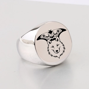 Detailed close-up of a silver signet ring featuring laser engraved wolf and moth patterns