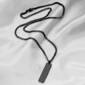 Macro view of a sleek black 40mm rectangular bar pendant on a matte cuban chain necklace