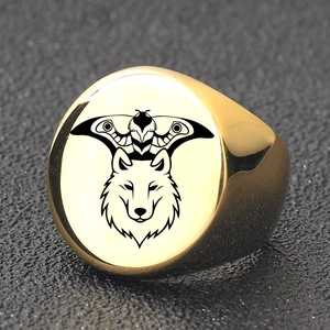 Detailed view of golden signet ring featuring a black wolf and moth engraving