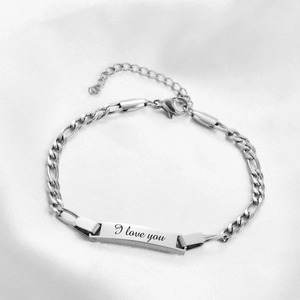 Detailed close-up of a silver Figaro chain bracelet with engraved I love you metal plate