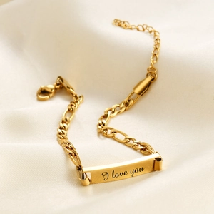 Detailed macro view of the gold Figaro chain bracelet with I love you engraved ID plate
