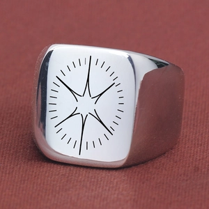 Gros plan de la bague chevalière en acier poli avec gravure d'étoile noire sur face carrée