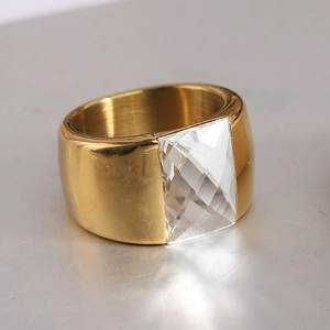 Vue détaillée d'une bague large en acier doré avec une grande pierre de verre facettée