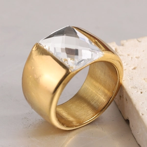 Gros plan d'une bague dorée brossée de 14mm de large avec une pierre carrée brillante