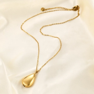 Close-up of golden teardrop urn necklace with screw bottom on soft silk background