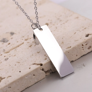Primer plano de un colgante rectangular de acero pulido en un soporte de piedra natural