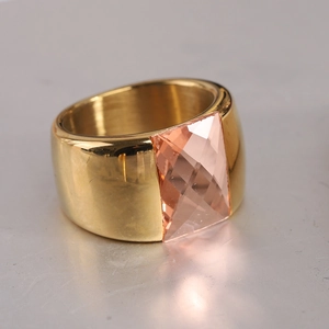 Vue latérale macro d'une large bague en acier doré sertie d'une pierre rose rectangulaire