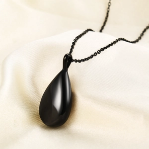 Polished black teardrop urn necklace on silk background minimalist jewelry style