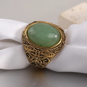 Vue macro d'une bague vintage dorée de 22mm avec pierre verte et gravure florale