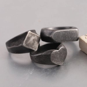 Macro shot of three vintage matte stainless steel rings with heart and geometric shapes