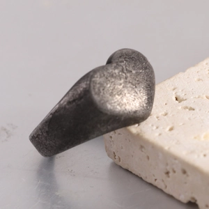 Macro detail of a vintage heart ring with distressed texture on a textured stone base