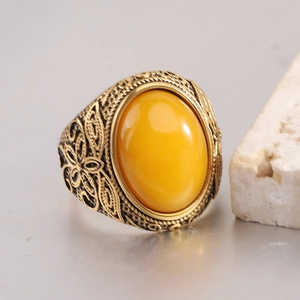 Détail de bague vintage dorée avec pierre jaune ovale et motifs floraux filigranes