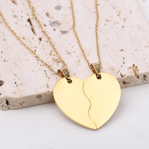 Polished gold stainless steel heart puzzle necklace set for couples on stone display