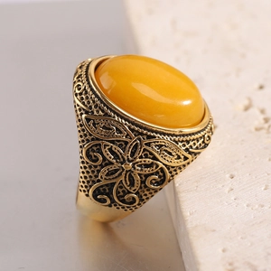 Détail d'une bague dorée vintage avec ambre jaune ovale et motifs floraux en relief