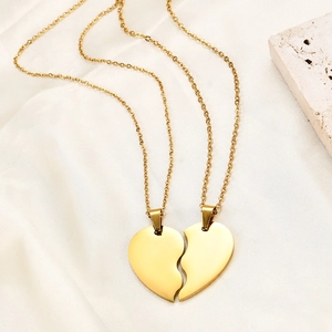 Detail of golden heart puzzle necklaces on silk fabric showing polished surface texture