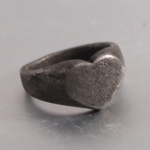 Detailed close-up of vintage heart signet ring with brushed metal texture and matte finish