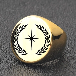 Macro shot of gold signet ring featuring star engraving and laurel leaf patterns