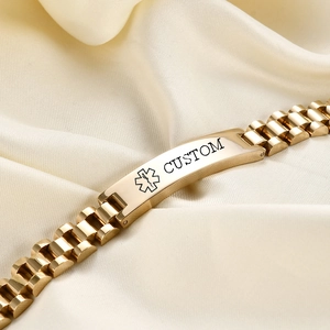 Detailed close-up of custom gold medical alert bracelet on silk fabric background