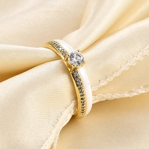 Detail of elegant gold ring featuring white ceramic inlay and sparkling zircon stones
