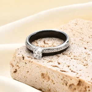 Macro detail of high-polish black ceramic ring with silver pavé diamonds and 4-prong zircon
