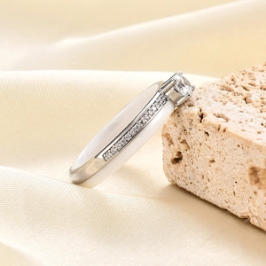 Detailed view of white ceramic ring with sparkling zircon stones on a silk backdrop