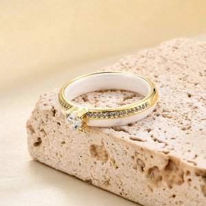 Macro detail of white ceramic ring with gold metal plating and sparkling pavé crystals