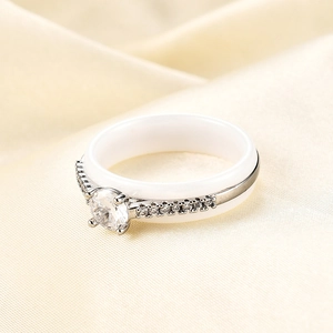 Macro-opname van 6mm witte keramische ring met ronde zirkoon op gele zijden achtergrond