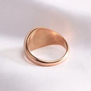 Macro view of rose gold signet ring with a polished mirror finish on silk background