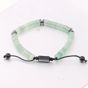 Macro shot of light green disc beads and hematite spacers on adjustable black braided cord