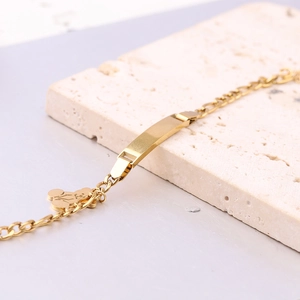 Detail eines 6mm Gold-Edelstahl-Armbands mit Bärenanhänger auf hellem Naturstein