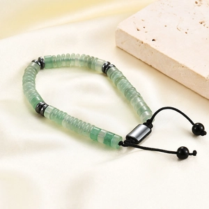 Detail of adjustable woven bracelet with green beads and metallic spacers on satin