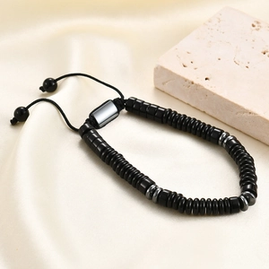 Detail of adjustable black beaded bracelet with metallic spacers on silk and stone