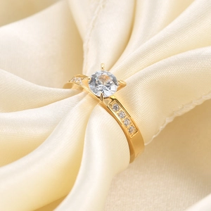 3mm gold plated zircon ring with round solitaire stone on soft silk fabric background