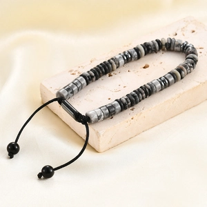 Close-up of natural map stone disk beads on an adjustable black braided cord bracelet
