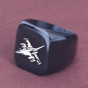 Detailaufnahme eines schwarzen Edelstahlrings mit lasergraviertem Kampfflugzeug-Motiv