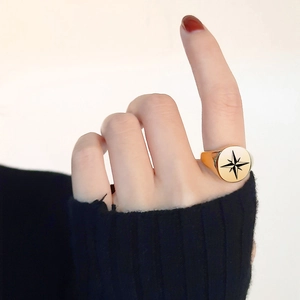 Close-up of gold stainless steel signet ring with black star compass on model