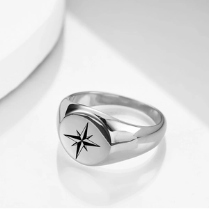 Macro detail of silver stainless steel signet ring with engraved black north star pattern