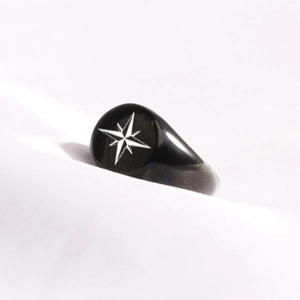 Macro shot of oval black signet ring featuring a white engraved eight-pointed star design