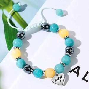 Dettaglio di un bracciale regolabile con perline, ciondolo a cuore, pietre e scritta HAPPY