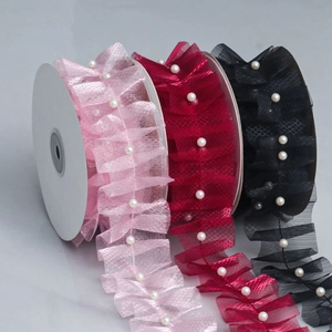 Detail of beaded pleated mesh lace trim in pink, wine red, and black on rolls